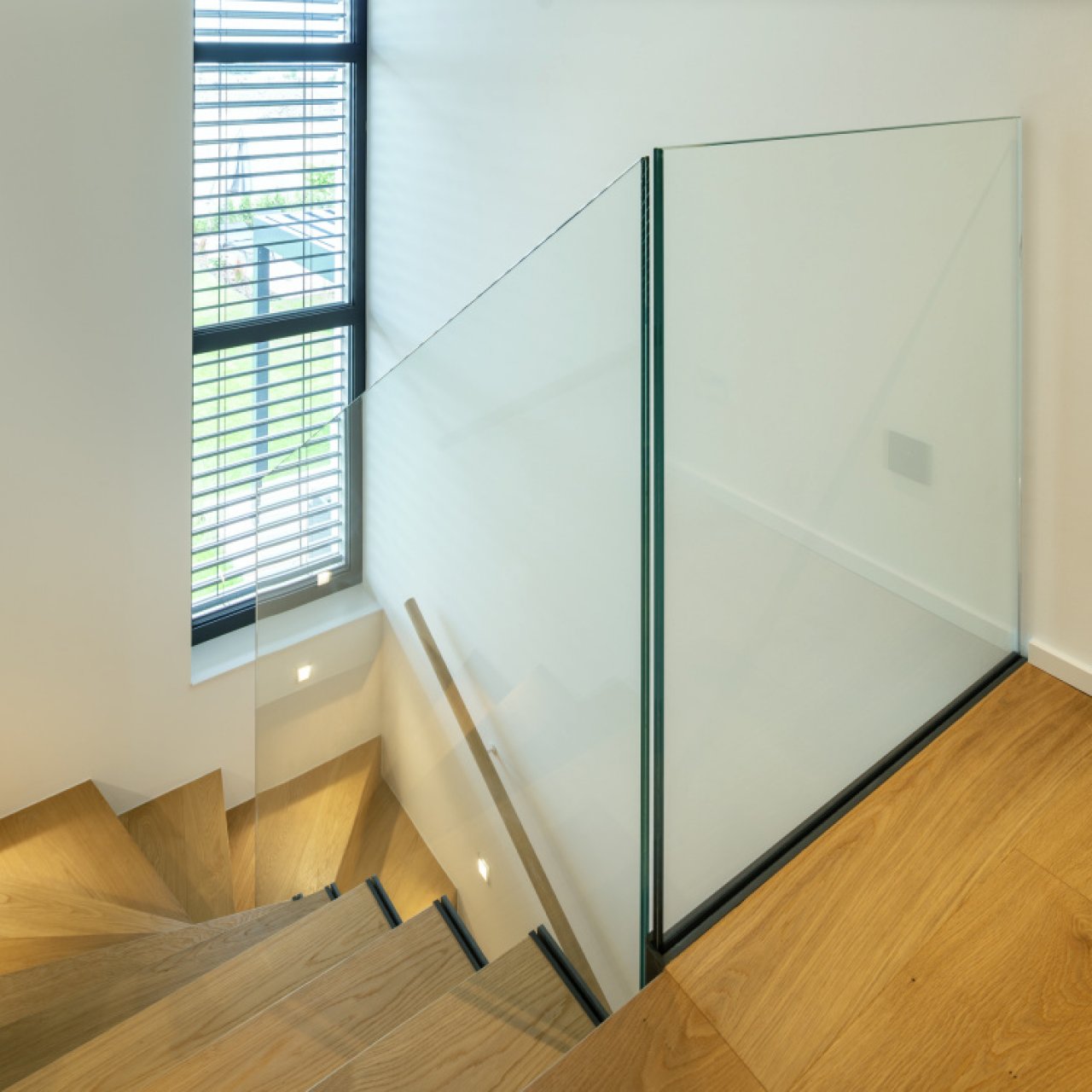 Elegantní skleněné zábradlí podél točitého schodiště